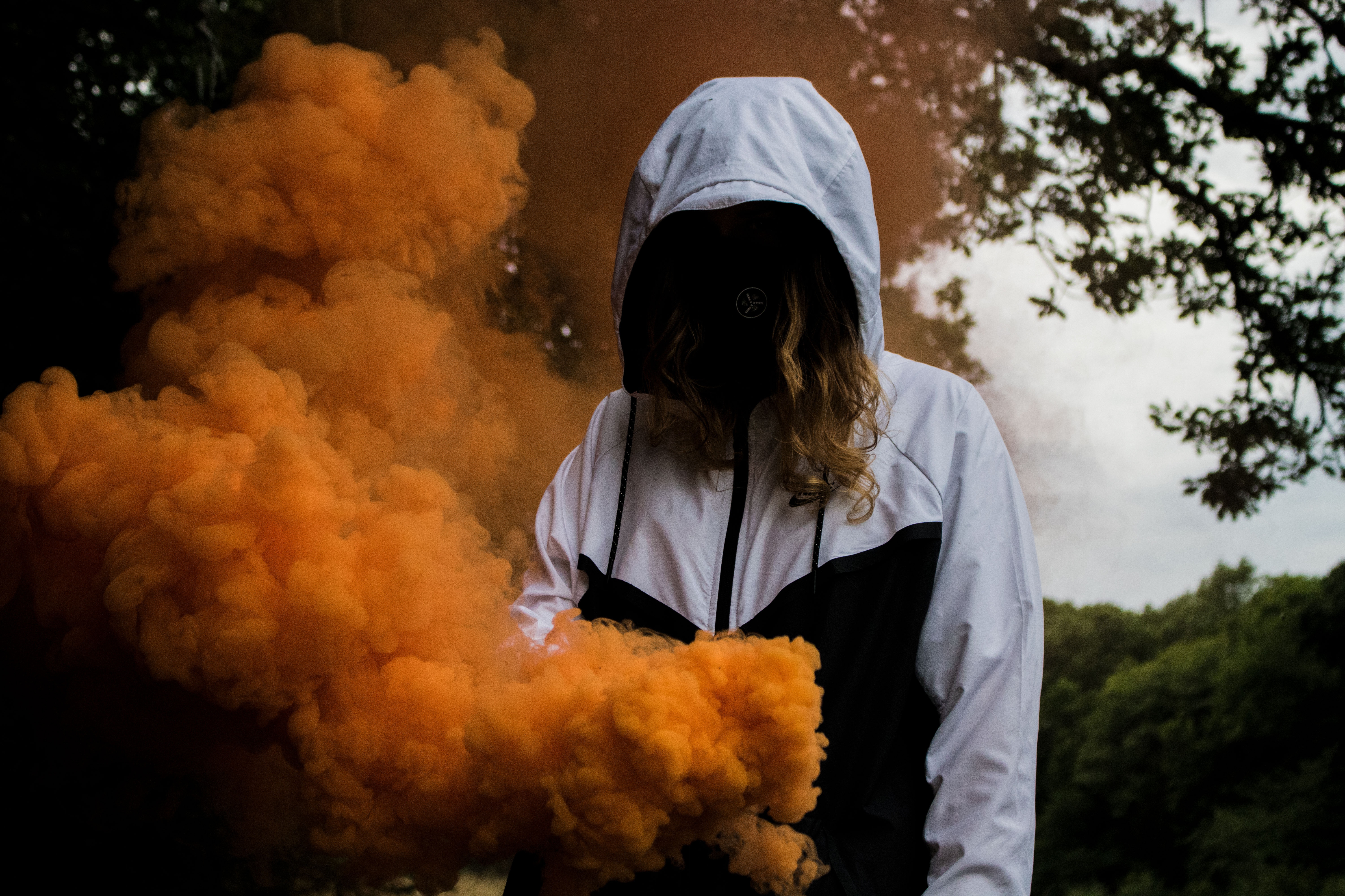 A person wearing a hooded jacket, surrounded by smoke